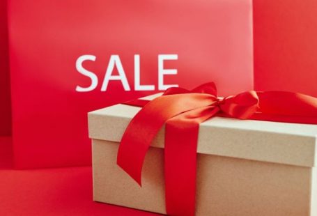 Luxury Shopping - Cardboard Box with Red Ribbon Beside A Sale Sign