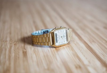 Gold Watch - square gold-colored analog watch on brown wooden board