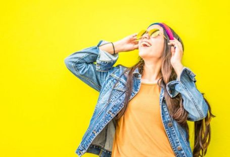 Fashion - Smiling Woman Looking Upright Standing Against Yellow Wall